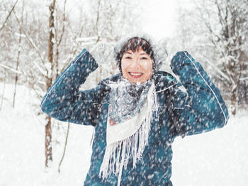 Smiling woman is playing with knitted hat. fun in snowy winter forest. woman laughs 