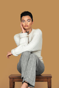 Portrait of young woman sitting against red background