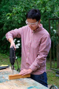 Carpenter using drill outdoors