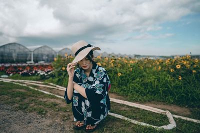 Woman wearing hat standing on field against sky