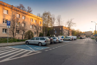 Cars on road by buildings in city against sky