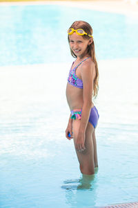 Portrait of young woman in bikini standing in swimming pool