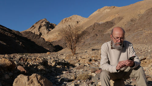 Senior man in the desert with smart phone 