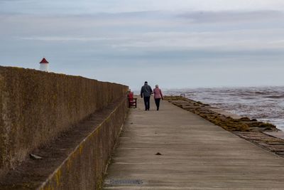 People on beach by sea against sky