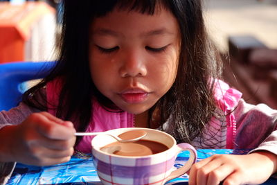 Close-up of cute girl having tea with spoon at home