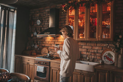 Portrait of candid authentic boy teenager holiday cooking in kitchen at wooden lodge xmas decorated