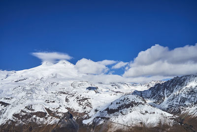 Scenic view of snowcapped mountains against blue sky