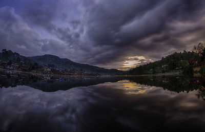 Scenic view of lake and mountains against storm clouds