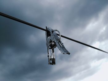 Low angle view of clothespin hanging on clothesline against cloudy sky during monsoon