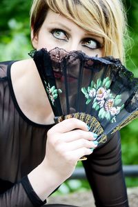 Close-up of woman covering face with hand fan