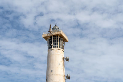 Low angle view of lighthouse by building against sky