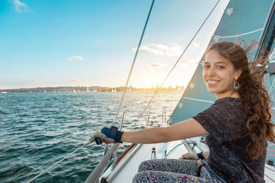 Beautiful young woman sailing in sea against sky