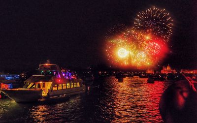 Firework display over river against sky at night