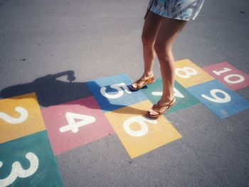 Low section of woman playing on hopscotch