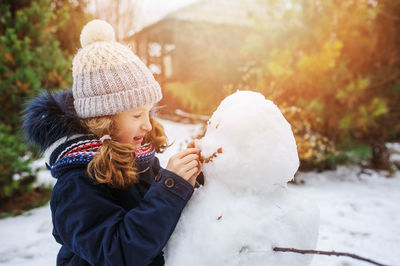 Girl making snowman in backyard