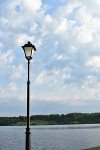 Street light by lake against sky