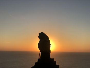 Silhouette statue against sea during sunset