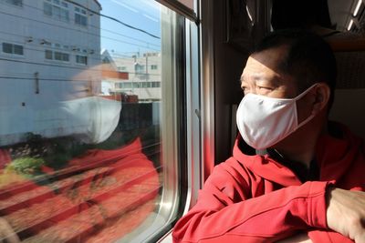 Man wearing mask looking through train window