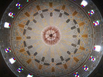 Low angle view of illuminated chandelier hanging from ceiling in building