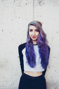 Portrait of beautiful young woman standing against wall