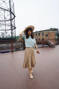 Portrait of smiling woman wearing hat walking on footpath