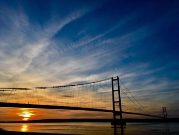 View of suspension bridge over river at sunset