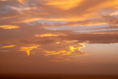 Scenic view of sea against dramatic sky during sunset