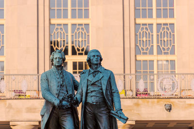 Statue of man standing against building