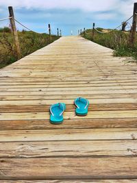 Empty wooden boardwalk against blue sky