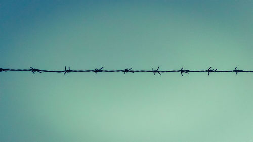 Low angle view of barbed wire against clear sky