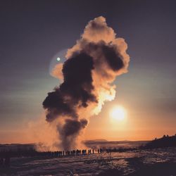 Steam emitting from geyser against sky during sunset