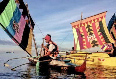 Man holding boat in sea against sky