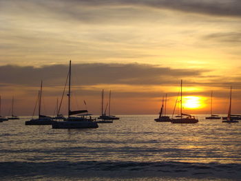 Sailboats sailing on sea against sky during sunset