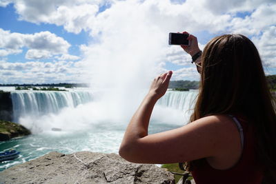 Woman photographing waterfall