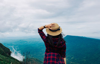 Rear view of woman standing on mountain against sky