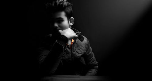 Portrait of boy looking away over black background