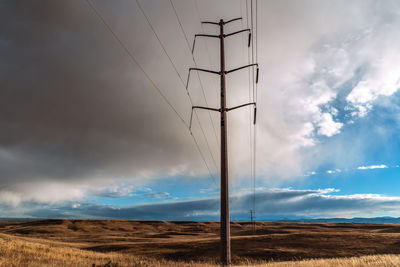 Low angle view of electricity pylon on land against sky