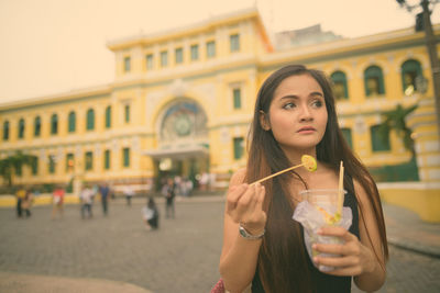 Portrait of woman holding ice cream outdoors