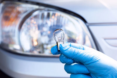 Mechanic holding light bulb against car