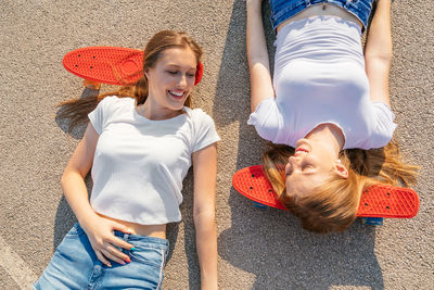Two teenage girls lying on concrete and holding hands