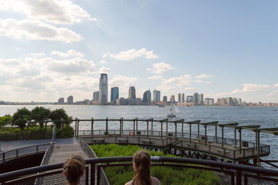 City at waterfront against cloudy sky