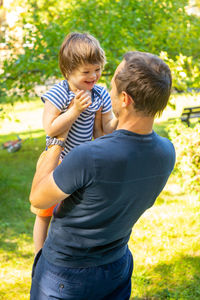 Rear view of father with son standing at park