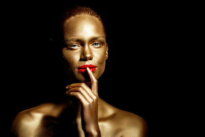 Portrait of woman with golden glitter make-up against black background