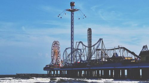 Amusement park by sea against sky