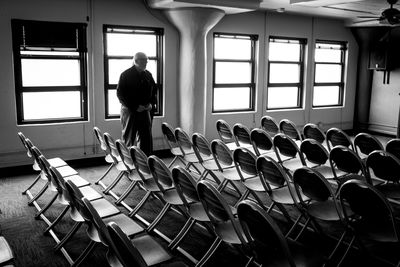 Senior man standing with chairs arranged in room