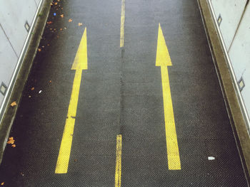 High angle view of yellow arrow symbol on road