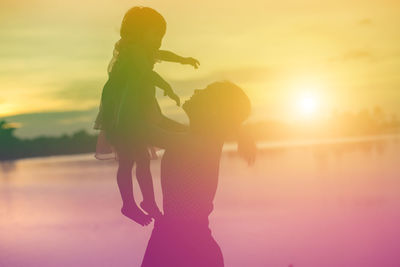 Side view of woman standing against sky during sunset