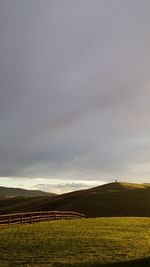 Scenic view of grassy field against cloudy sky