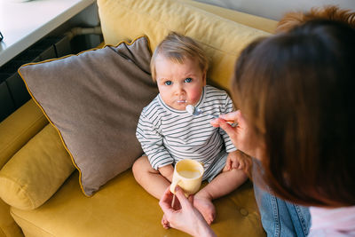 Mom feeds a small child at home with yogurt from a spoon. family concept