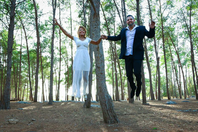 Full length of happy friends standing in forest